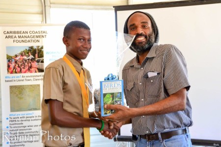 Brahim Diop, Forestry Dept. Jamaica, hands out prizes to student winners of the Bird Art Competition organized by C-CAM (Caribbean Coastal Area Management Foundation) in partnership with NEPA (National Environment and Planning Agency), the Forestry Department, and the Institute of Jamaica.