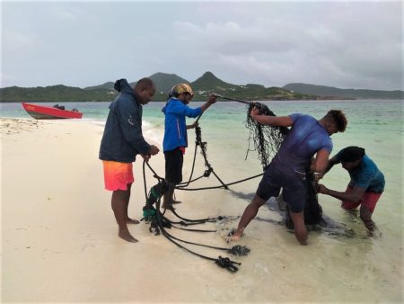 Removing litter, old fishing net, from seabird nesting cay beach.