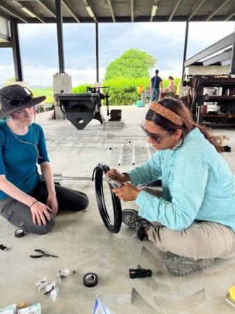 Ivelisse Rodrigues practices stripping coaxial cables and attaching connectors with Mallory Sarver.