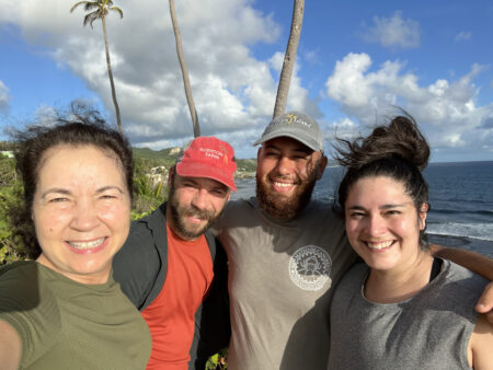 Motus team in Barbados, standing by the sea with palm trees in the background