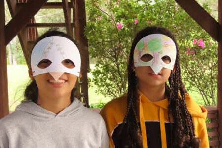 Two children wearing bird masks they have made 
