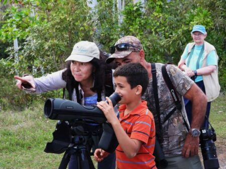 Lisa Sorenson and guide Ernesto Reyes showing a young boy some birds in Cuba.