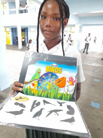 Photo of young girl with her prizes- bird book, bird ID sheet and stickers