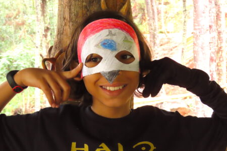 A young girl models her bird mask.