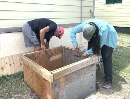 Photo of a man and woman constructing a box base.