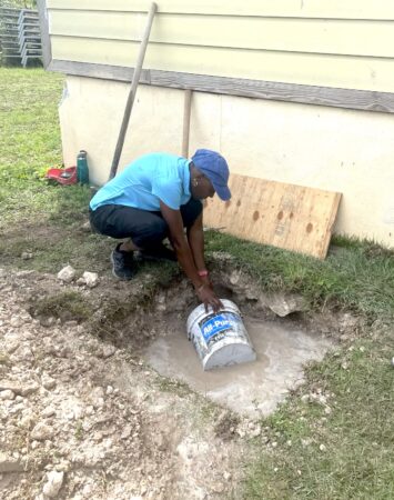 Photo of a woman using a bucket to remove water from a hole in the ground