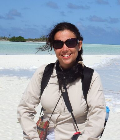 Zoomed in photo of woman standing on white sand beach.