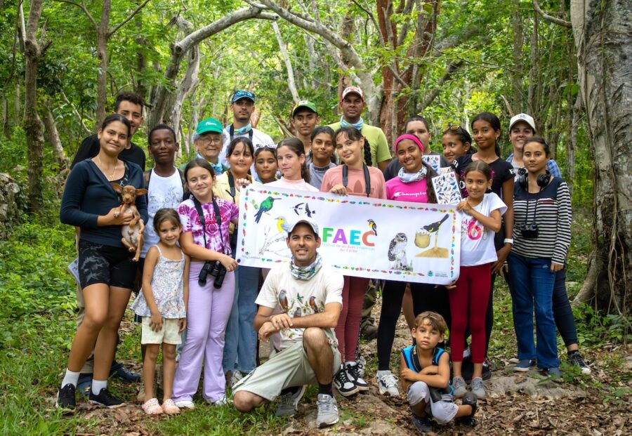 Group photo of children and teenagers on a trail in a lagoon. They are also holding a FAEC flag in the middle.