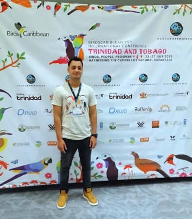 Photo of a man standing in front of a media backdrop.