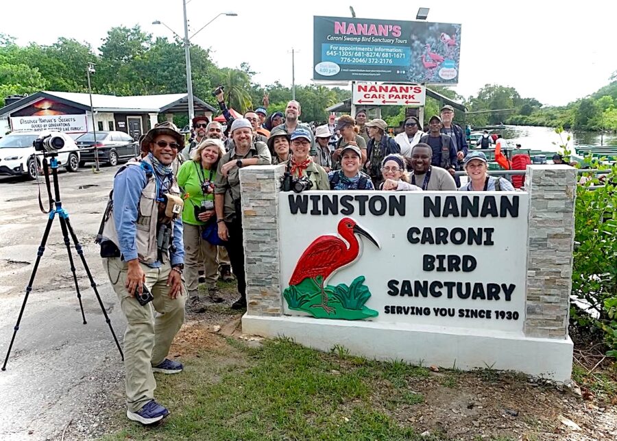 Group photo of a tour group surrounding the Caroni Bird Sanctuary sign.