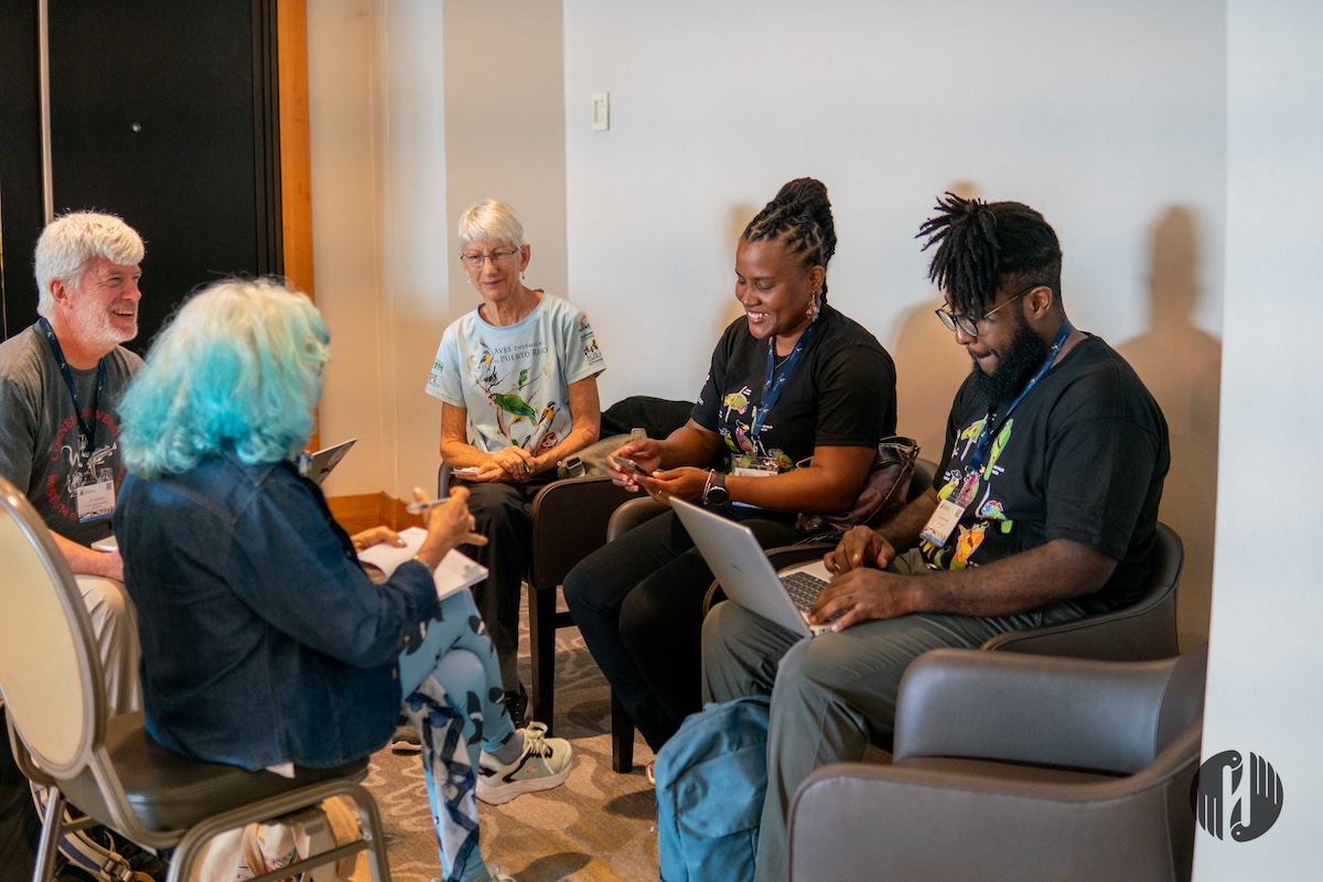 Photo of a group of people sitting in a circle and working together. 